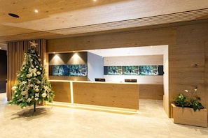 Ein Empfangsbereich mit Weihnachtsbaum, Holzbude an der Rezeption und einem großen Fenster mit Blick auf die Stadt.