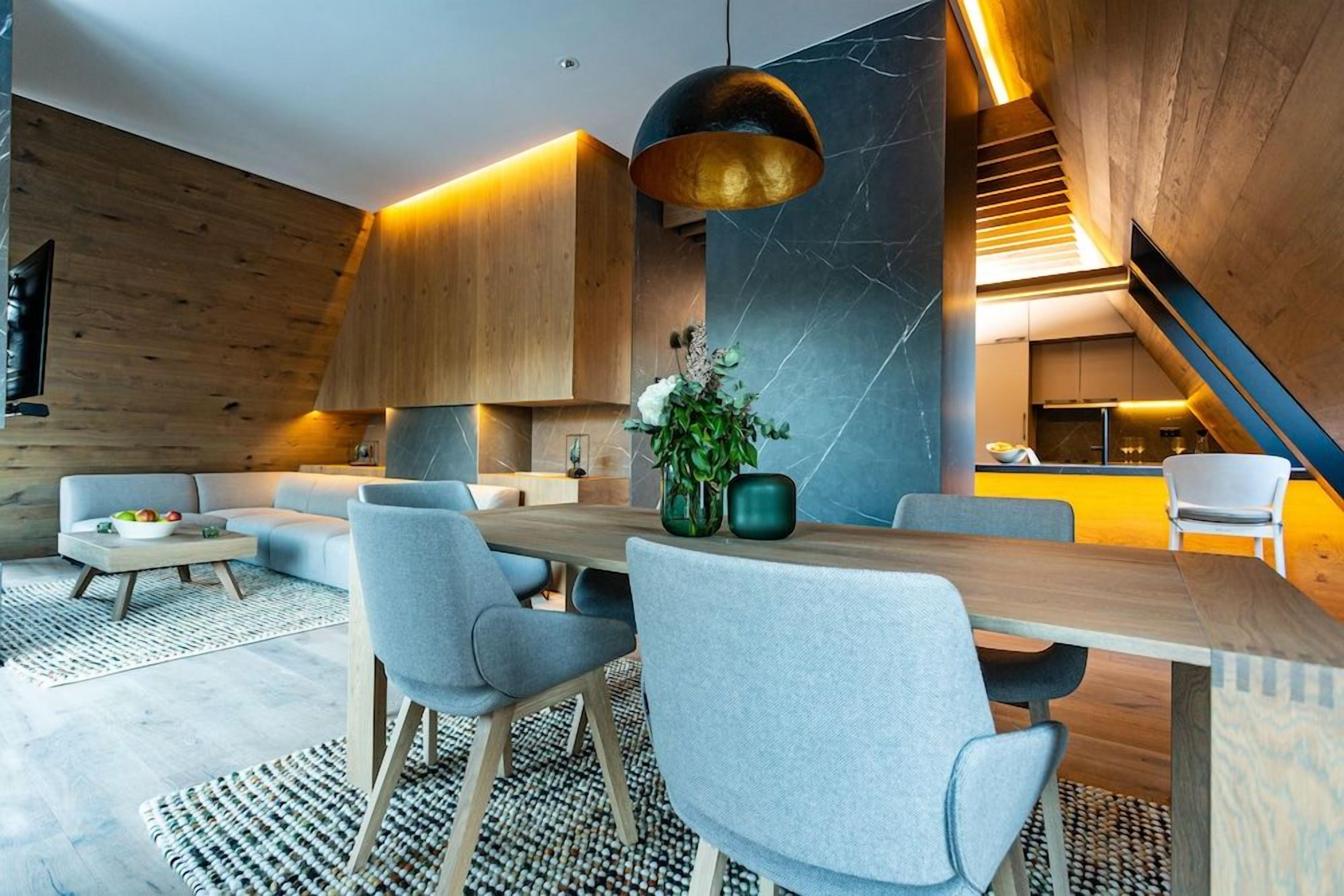 A modern interior with a dining area, sofas, and a staircase.