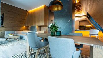 A modern interior with a dining area, sofas, and a staircase.