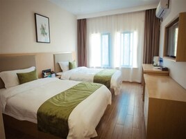 Una habitación de hotel con dos camas, un escritorio y una ventana con cortinas.