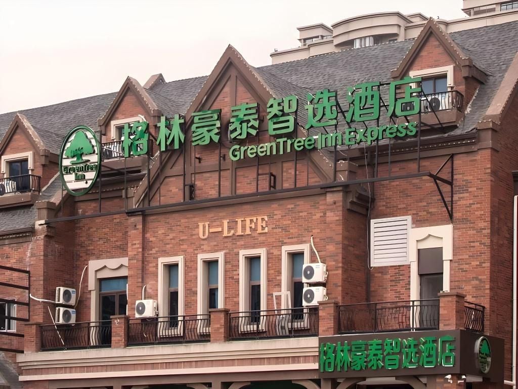 A hotel with a green sign indicating it is a GreenTree Inn Express.
