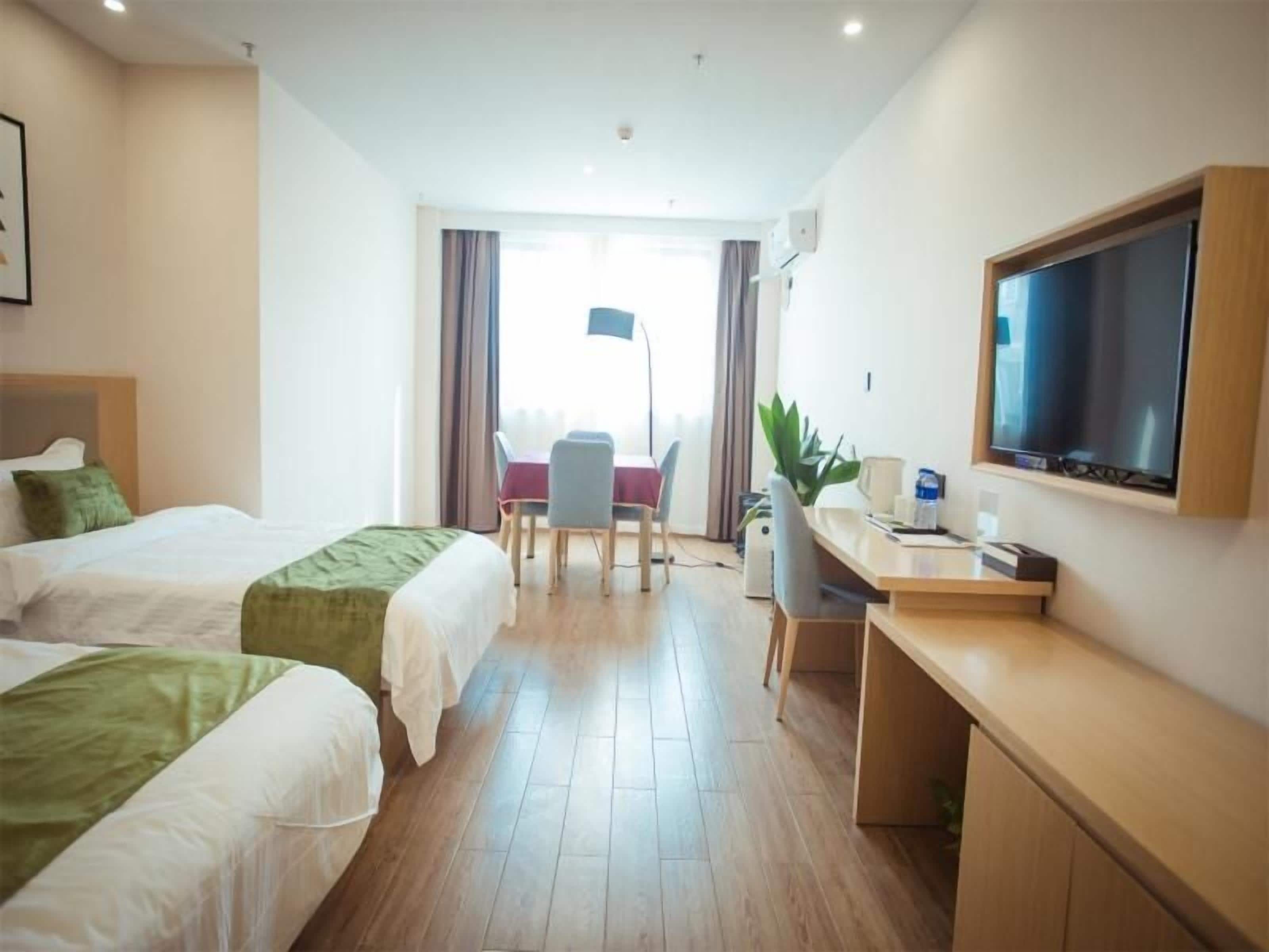 A hotel room with two beds, a desk, a television, and a view of the outdoors.