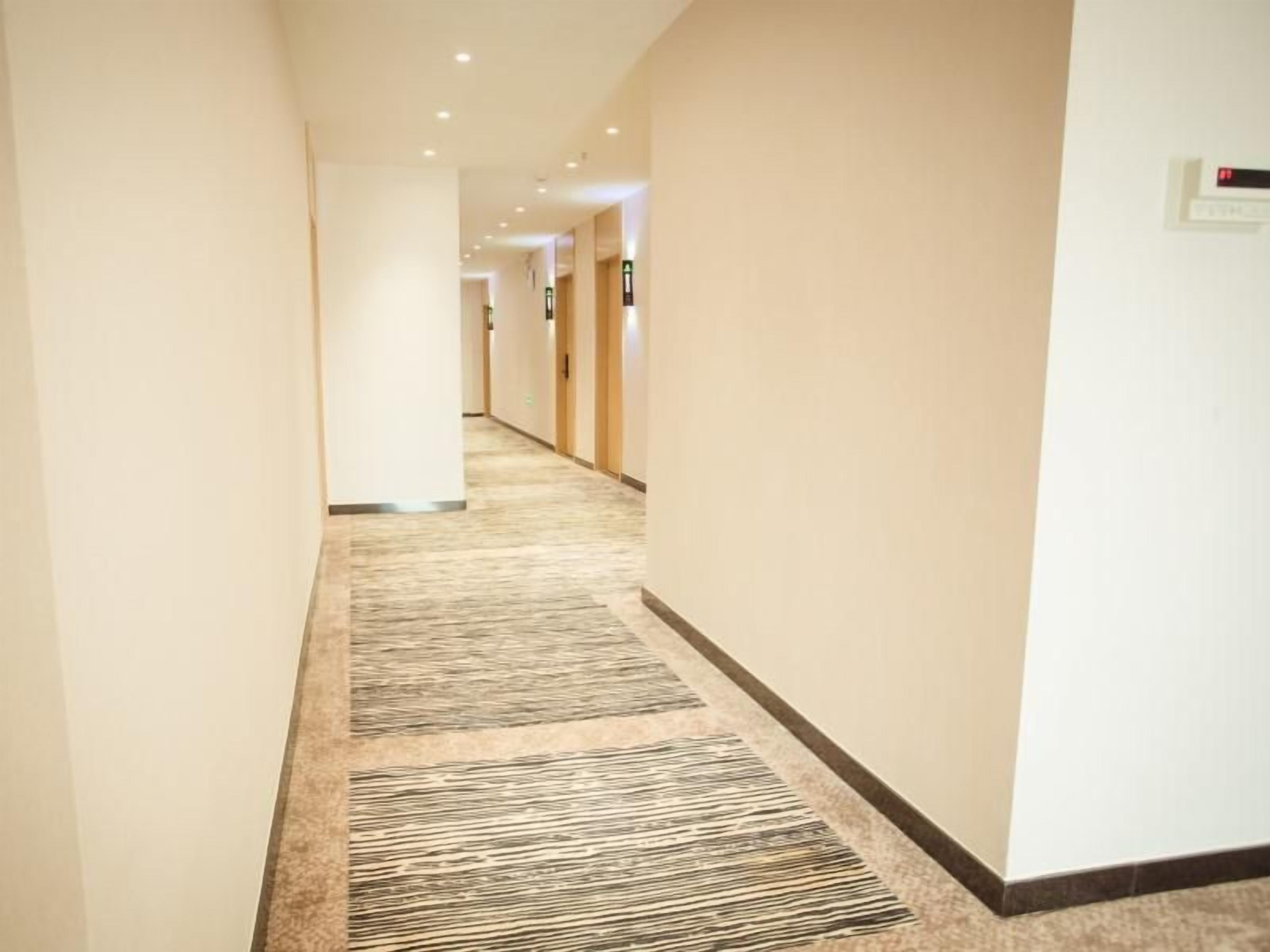 Un couloir d'hôtel avec un revêtement de sol en moquette et des portes de chaque côté.