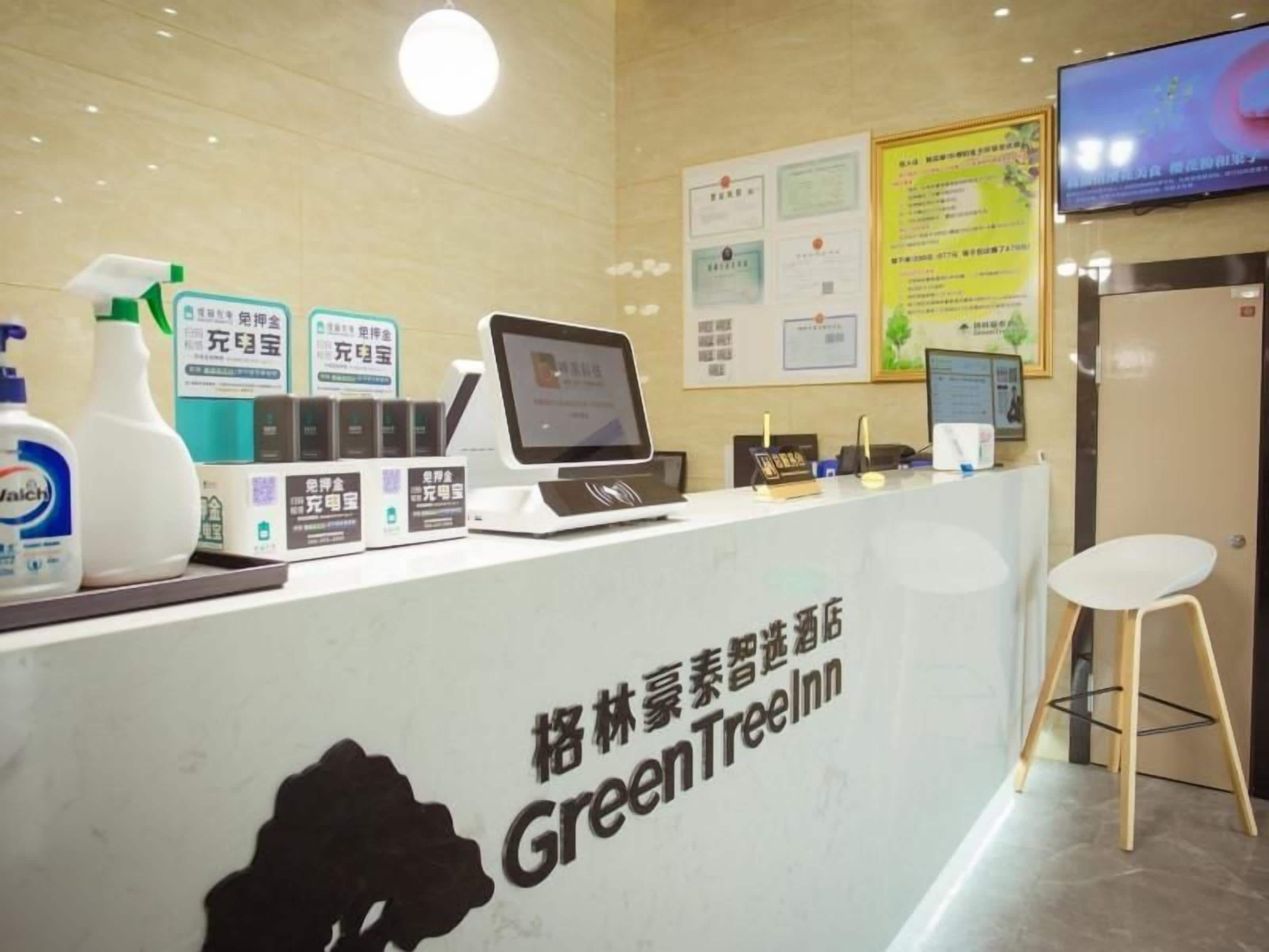 A reception desk with a computer, a chair, and various items on the counter.