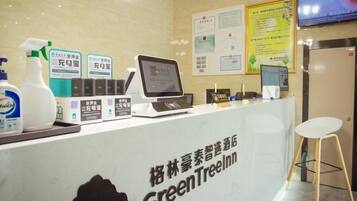 A reception desk with a computer, a chair, and various items on the counter.