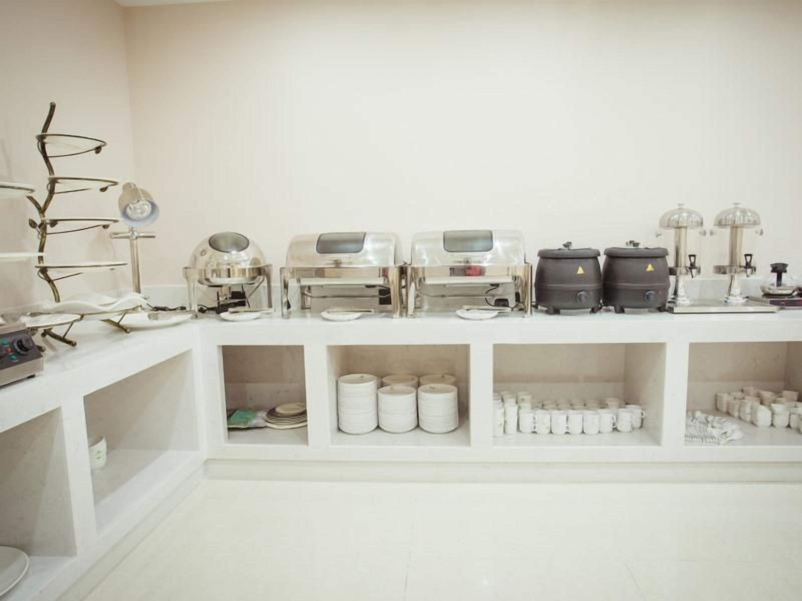 A clean, white room with shelves containing various kitchen appliances and utensils.
