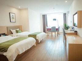 Habitación de hotel con dos camas, un escritorio, una silla y un ventanal.
