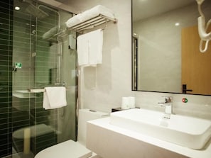 Een moderne badkamer met een douchecabine van glas, een wit wastafelmeubel en een grote spiegel.