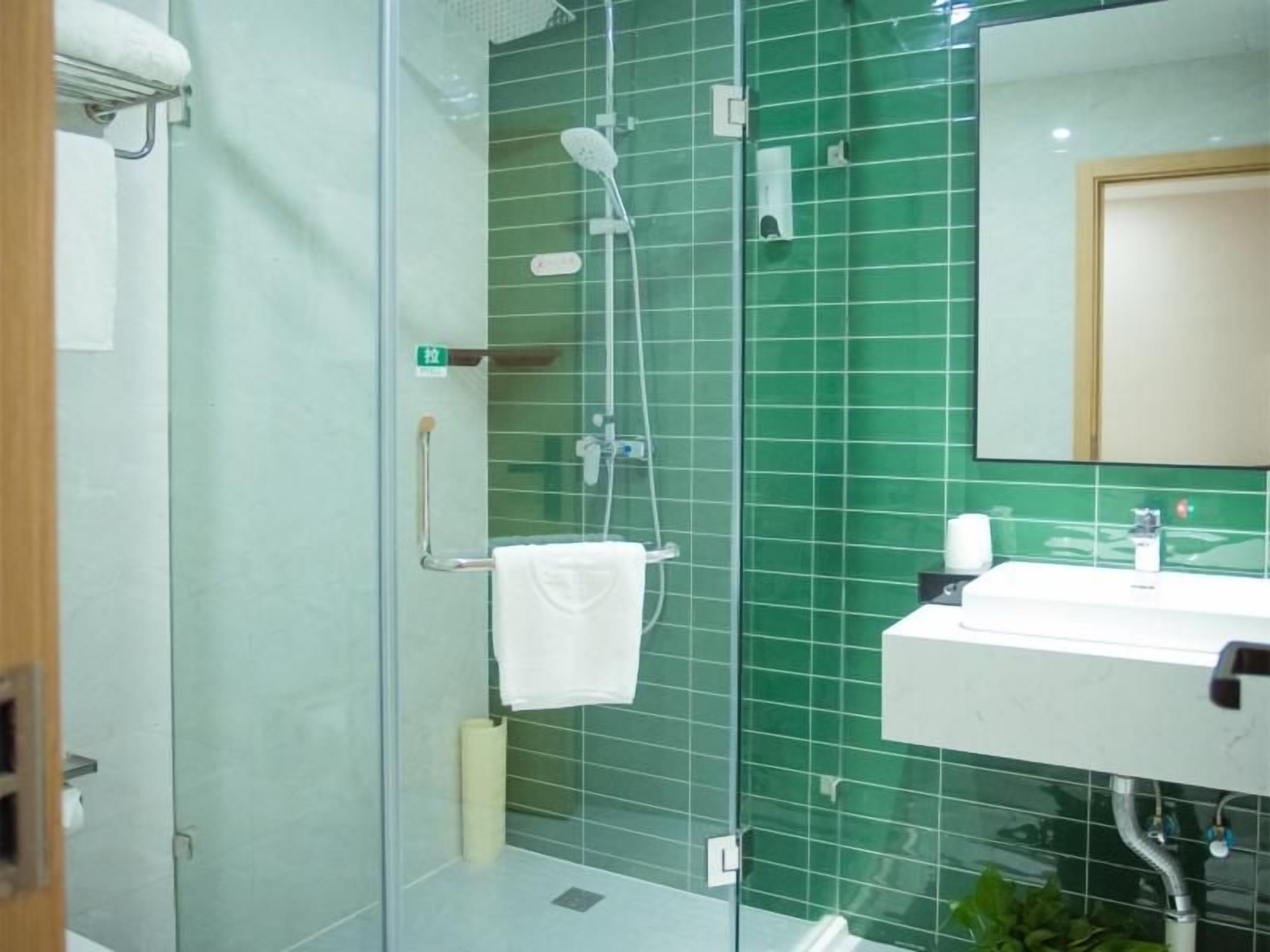 A bathroom with a glass shower enclosure, a white sink, and a mirror.