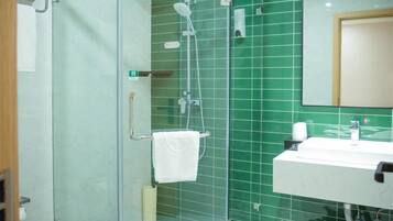 A bathroom with a glass shower enclosure, a white sink, and a mirror.