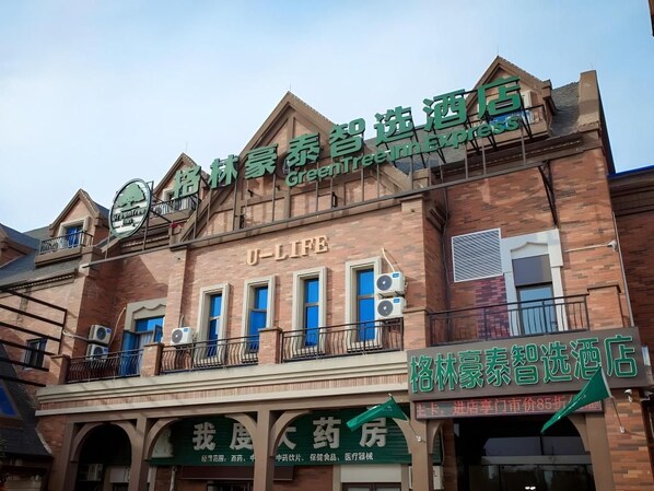 Een hotel met een groen bord waarop staat dat het een GreenTree Inn Express is.