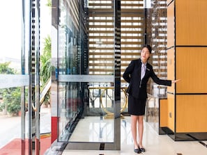 A hotel lobby with a modern design, featuring a glass entrance, a wooden reception desk, and a staircase leading to an upper level. - Chonpines Hotel (Shenzhen)