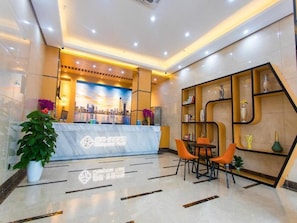 A hotel reception area with a marble counter, seating, and decorative shelves. - Chonpines Hotel (Shenzhen)