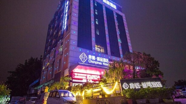 Un edificio de hotel de varios pisos con señalización iluminada y una entrada destacada.