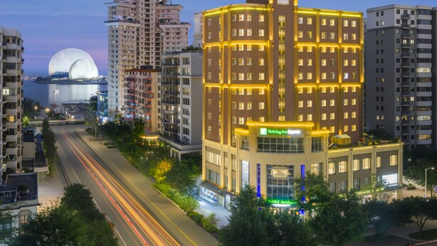 A multi-story hotel with a prominent corner entrance, large windows, and a visible Holiday Inn Express sign. - Atour Light (Zhuhai)