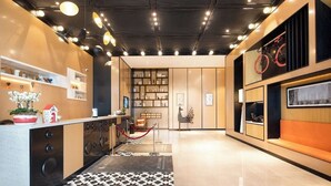 En moderne hotellobby med reception, siddepladser og en reol.