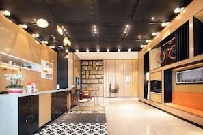 Eine moderne Hotelhalle mit Rezeption, einer Sitzecke und einem Bücherregal.