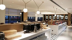 Et moderne restaurantinteriør med en lang disk, hængende pendellamper og et flisegulv.