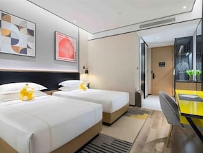 Ein Hotelzimmer mit zwei Betten, einem Schreibtisch und einem Spiegel.