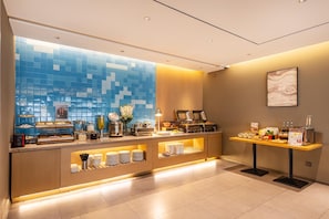 A modern hotel lobby with a reception desk, buffet area, and a large window with blue-tiled walls. - Home Inn (Tianjin)