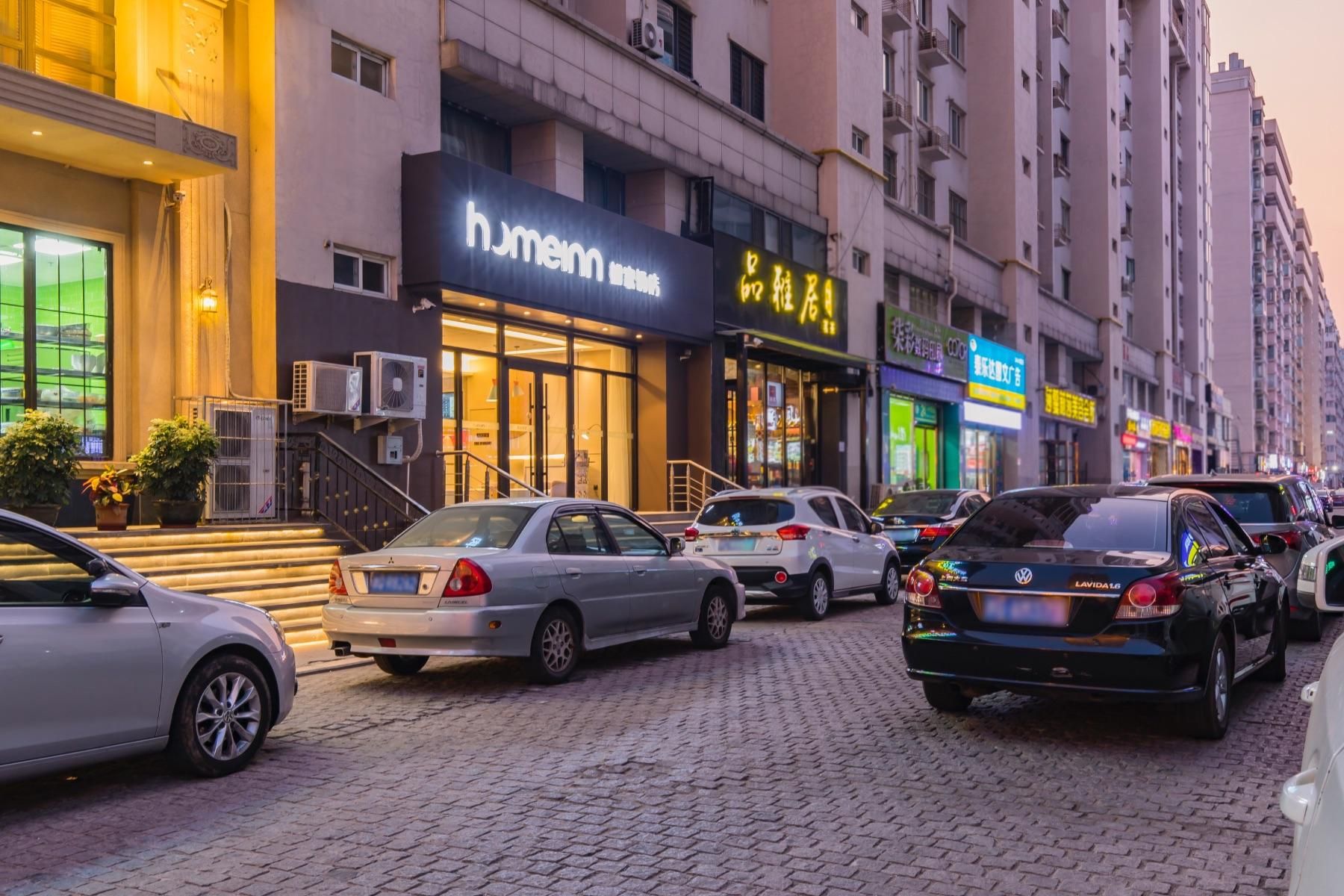 A street with parked cars and a building with a sign that reads 'humenn'.