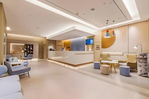 A modern reception area with a reception desk, seating, and a TV screen. - Home Inn (Tianjin)