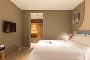 Habitació d'hotel amb un llit, una televisió, un escriptori i un bany visible per una porta oberta.