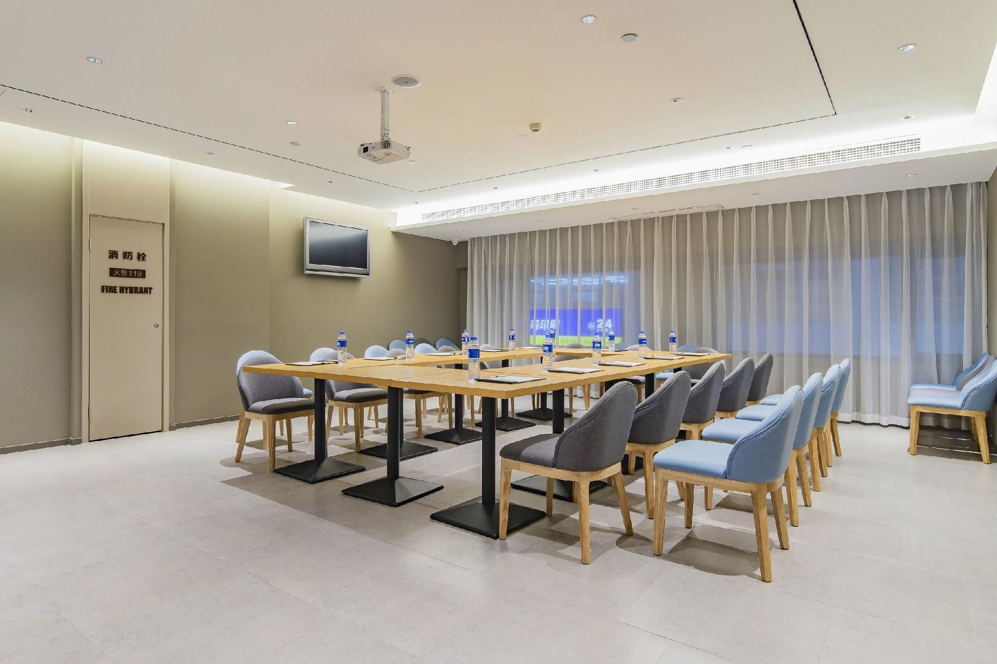A conference room with a long table, chairs, a projector, and a screen.