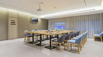 A conference room with a long table, chairs, a projector, and a screen.