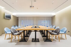 A conference room with a long table, chairs, a projector, and a TV on the wall. - Home Inn (Tianjin)