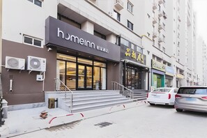 Hotel amb façana moderna, una escala que condueix a l'entrada i una zona d'aparcament amb cotxes.