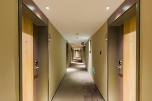 A hotel corridor with doors on both sides, a carpeted floor, and a ceiling with recessed lighting. - Home Inn (Tianjin)