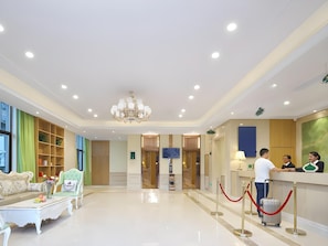 A hotel lobby with a reception desk, a chandelier, a sofa, and a bookshelf. - Vienna 3 Best Hotel (Lu'an)