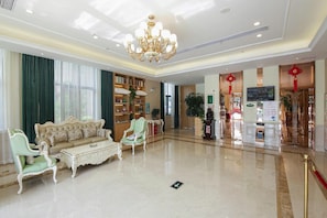 Un'ampia hall con un lampadario, un divano, una libreria e una reception.