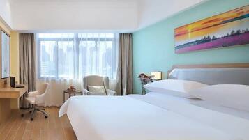 Una habitación de hotel con una cama grande, dos sillas, un escritorio y un ventanal con cortinas.