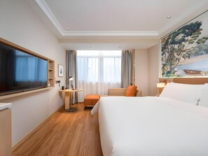Una camera d'albergo con un letto grande, una scrivania, una televisione e un quadro appeso al muro.