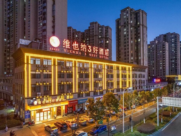 Un hotel su più piani con insegne illuminate, un ristorante a livello strada e un'area di parcheggio.