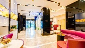 Um lobby de hotel moderno com balcão de recepção, área de estar e vista para a entrada.