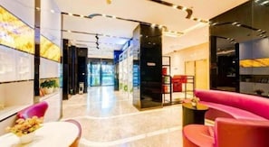 Un moderno vestíbulo de hotel con una recepción, zona de estar y vistas al acceso.