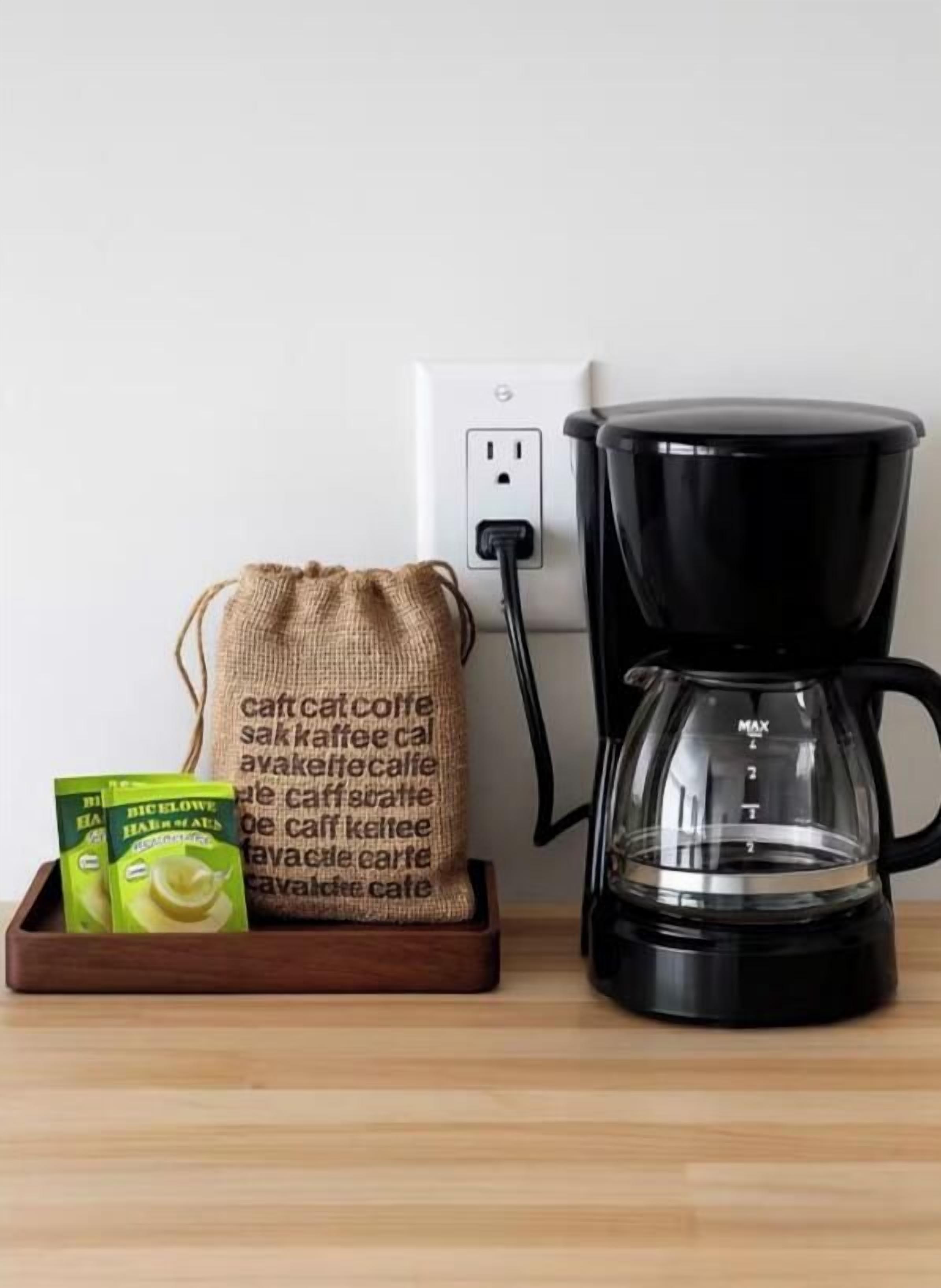 A coffee maker, a burlap sack, and coffee pods on a wooden surface.