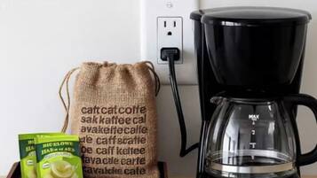 A coffee maker, a burlap sack, and coffee pods on a wooden surface.