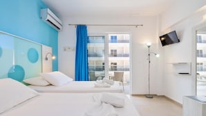 Una camera d'albergo con due letti, televisione, finestra con tende e vista sulla facciata dell'edificio.