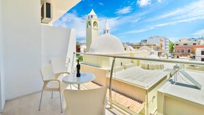Un balcone con tavolo, sedie e una bottiglia di vino.