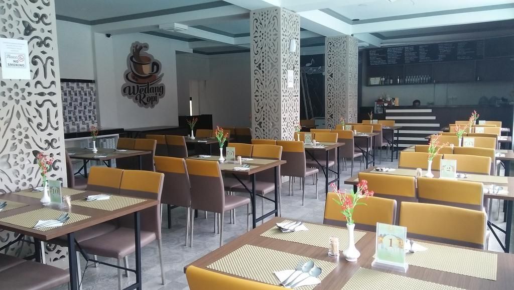 A restaurant with multiple tables and chairs, a menu board, and a logo on the wall.