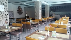 A restaurant with multiple tables and chairs, a menu board, and a logo on the wall. - Hotel Sun Q Ta Guci (Songgom)