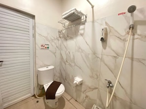 Un baño con inodoro, ducha y perchero para toallas.