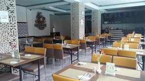 A restaurant with multiple tables and chairs, a menu board, and a logo on the wall. - Hotel Sun Q Ta Guci (Songgom)