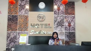 Hotellin vastaanottotiski, jonka yläpuolella on kello ja jonka yläpuolella on kyltti, jossa lukee: ”HOTEL Sautiita CUSI”.