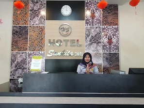Un mostrador de recepción de hotel con un reloj encima y un cartel que dice 'HOTEL Sautiita CUSI'.