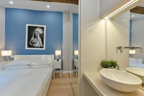 A hotel room with a bed, bedside tables, a large mirror, and a wall-mounted picture. - Ponte Vecchio Deluxe (Florence)